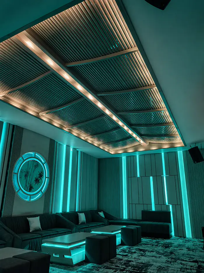 Ruang karaoke privat V-KTV PIK 2 dengan pencahayaan cyan dan panel kayu